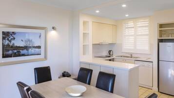 Una cocina moderna con armarios blancos, una isla integrada y un comedor con mesa y sillas.