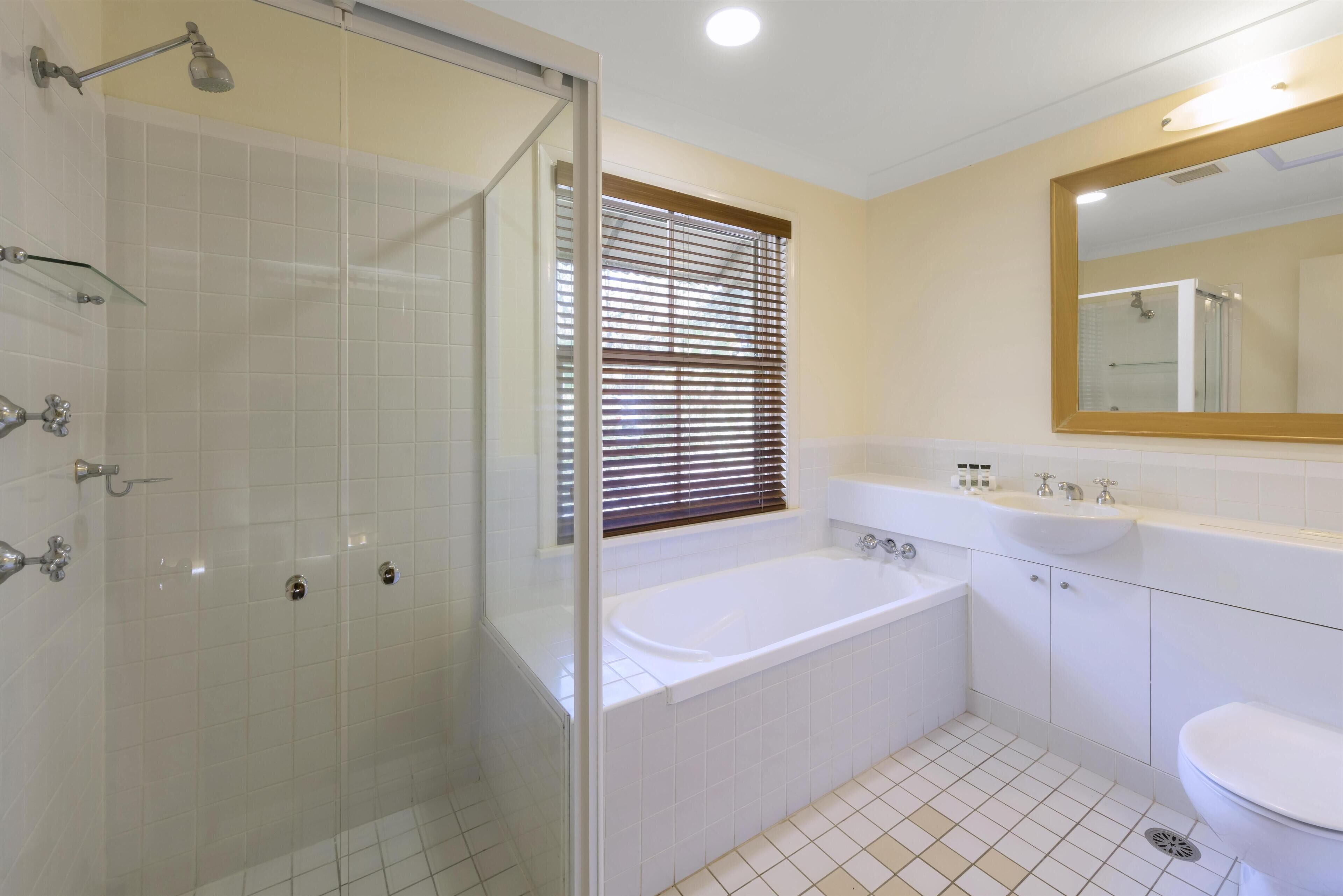 A modern bathroom with a glass-enclosed shower, a freestanding bathtub, a sink, and a toilet.
