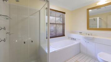 A modern bathroom with a glass-enclosed shower, a freestanding bathtub, a sink, and a toilet.