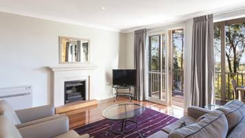 Un salón moderno con chimenea, un televisor de pantalla plana y un gran ventanal con cortinas.
