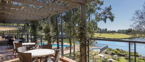 Un área de patio al aire libre con piscina, mesas y sillas de comedor.