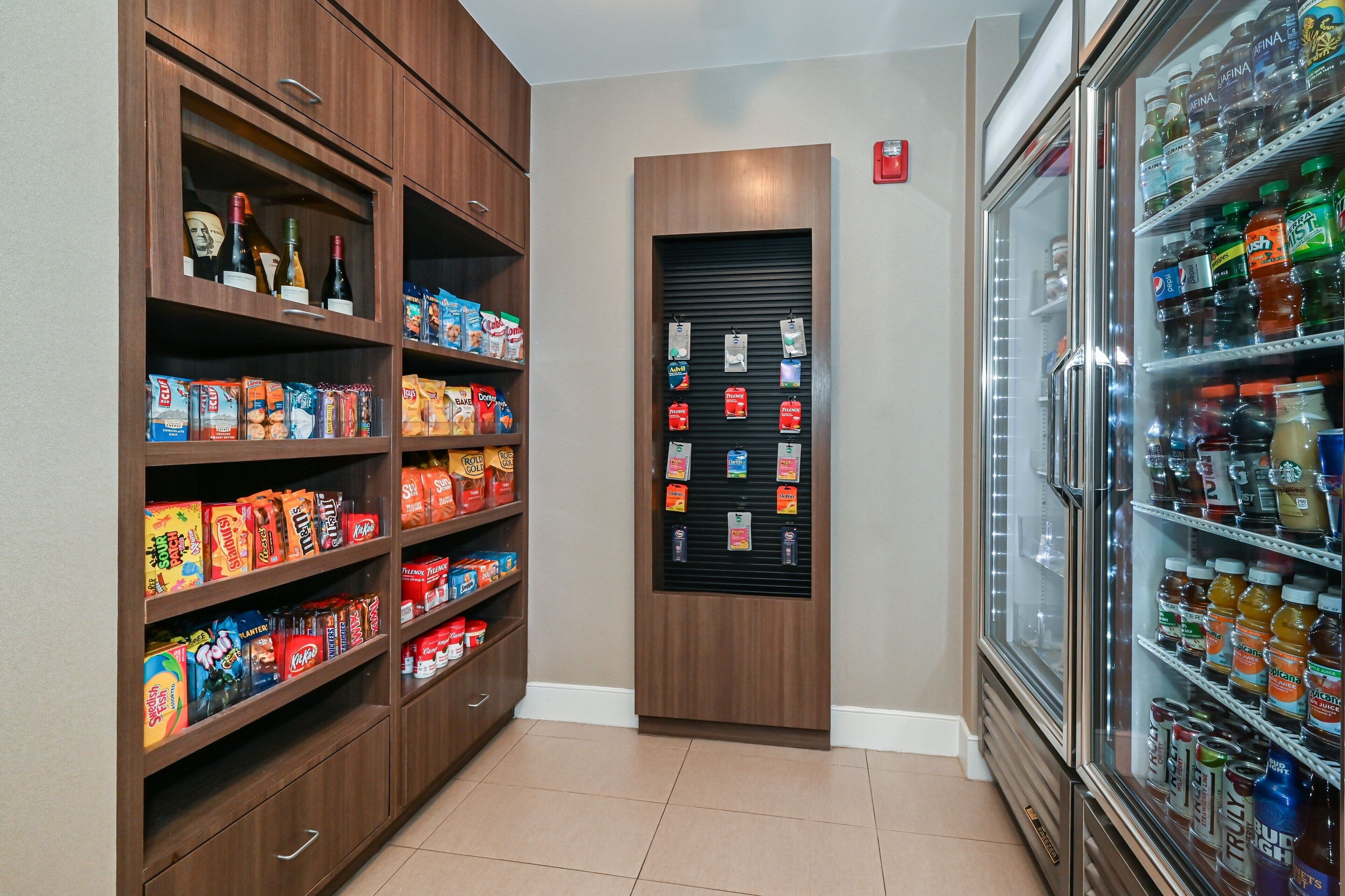 A well-stocked beverage refrigerator and shelves with snacks and beverages.