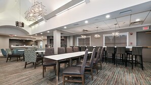 Uma sala de conferências espaçosa com uma mesa comprida e cadeiras, tapete estampado e luminárias modernas.