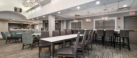 A spacious conference room with a long table and chairs, a patterned carpet, and modern lighting fixtures.