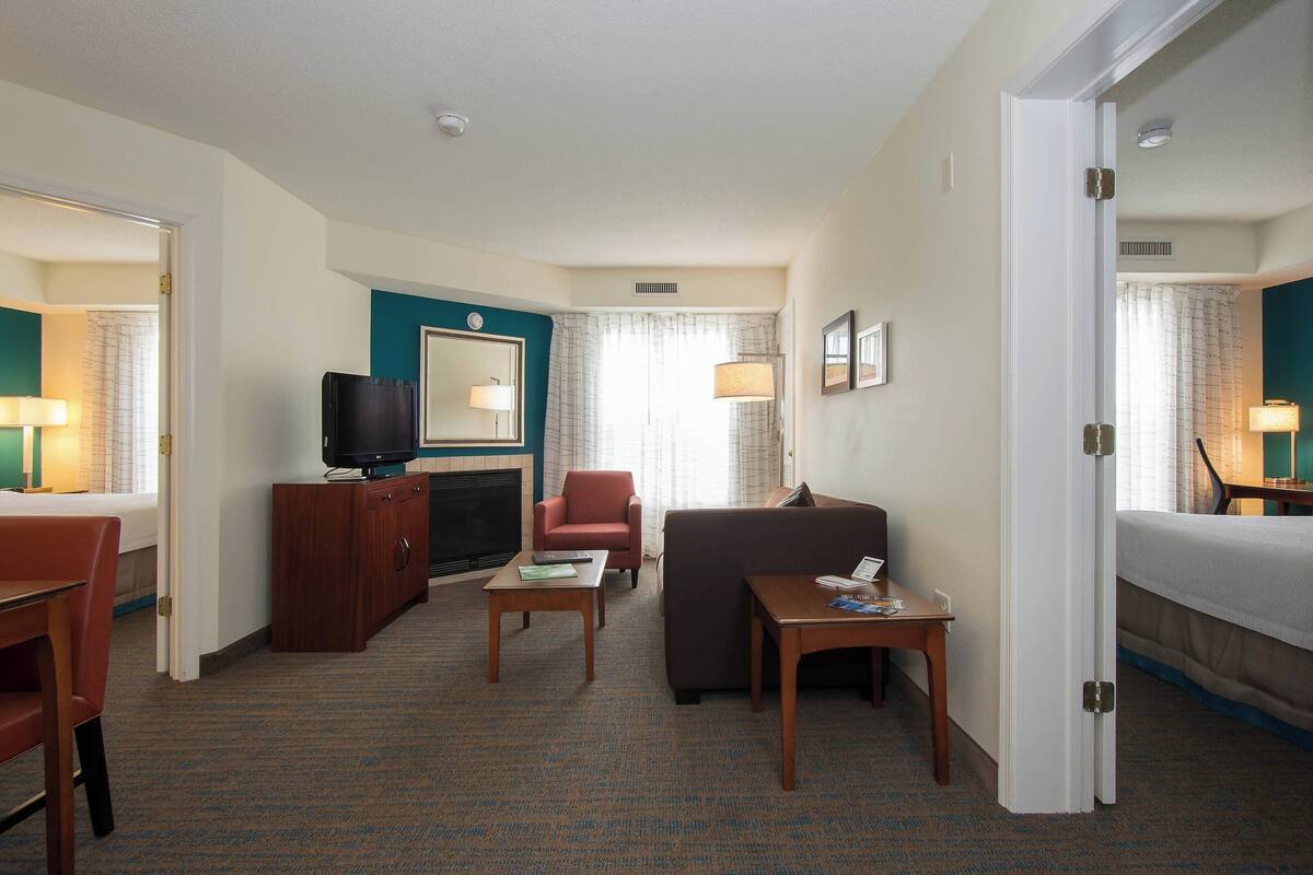 A hotel room with a bed, a sofa, a television, a desk, and a chair.