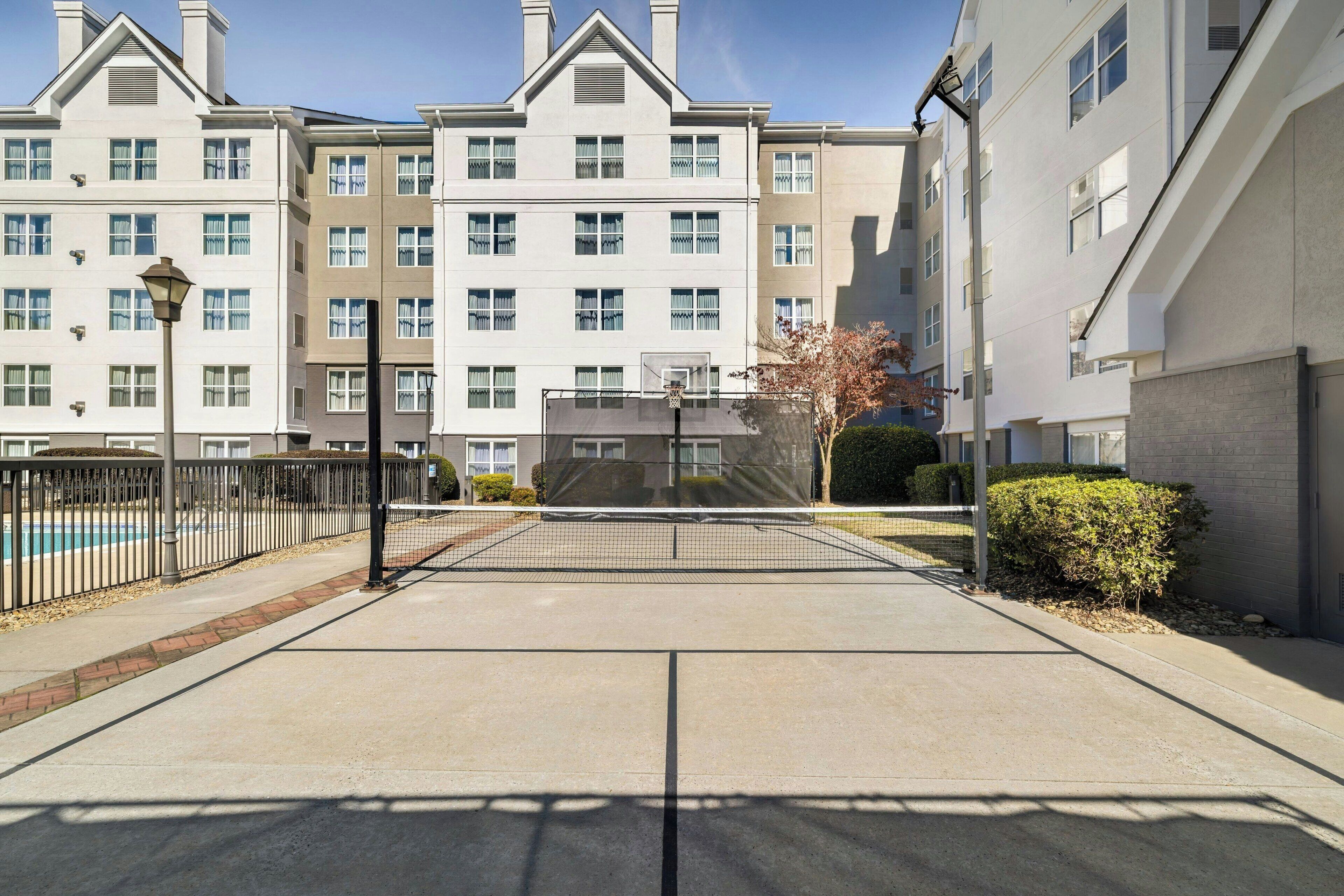Un edificio residencial con una cancha de baloncesto al frente.