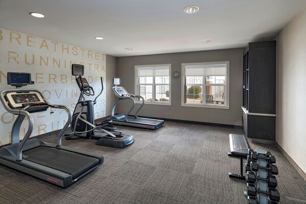 Une salle de sport équipée de tapis de course, d’un vélo d’appartement et d’haltères.
