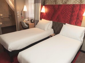 A hotel room with two single beds, a desk with a chair, a telephone, and a red accent wall. - Ibis Glasgow City Centre – Sauchiehall St (Glasgow)