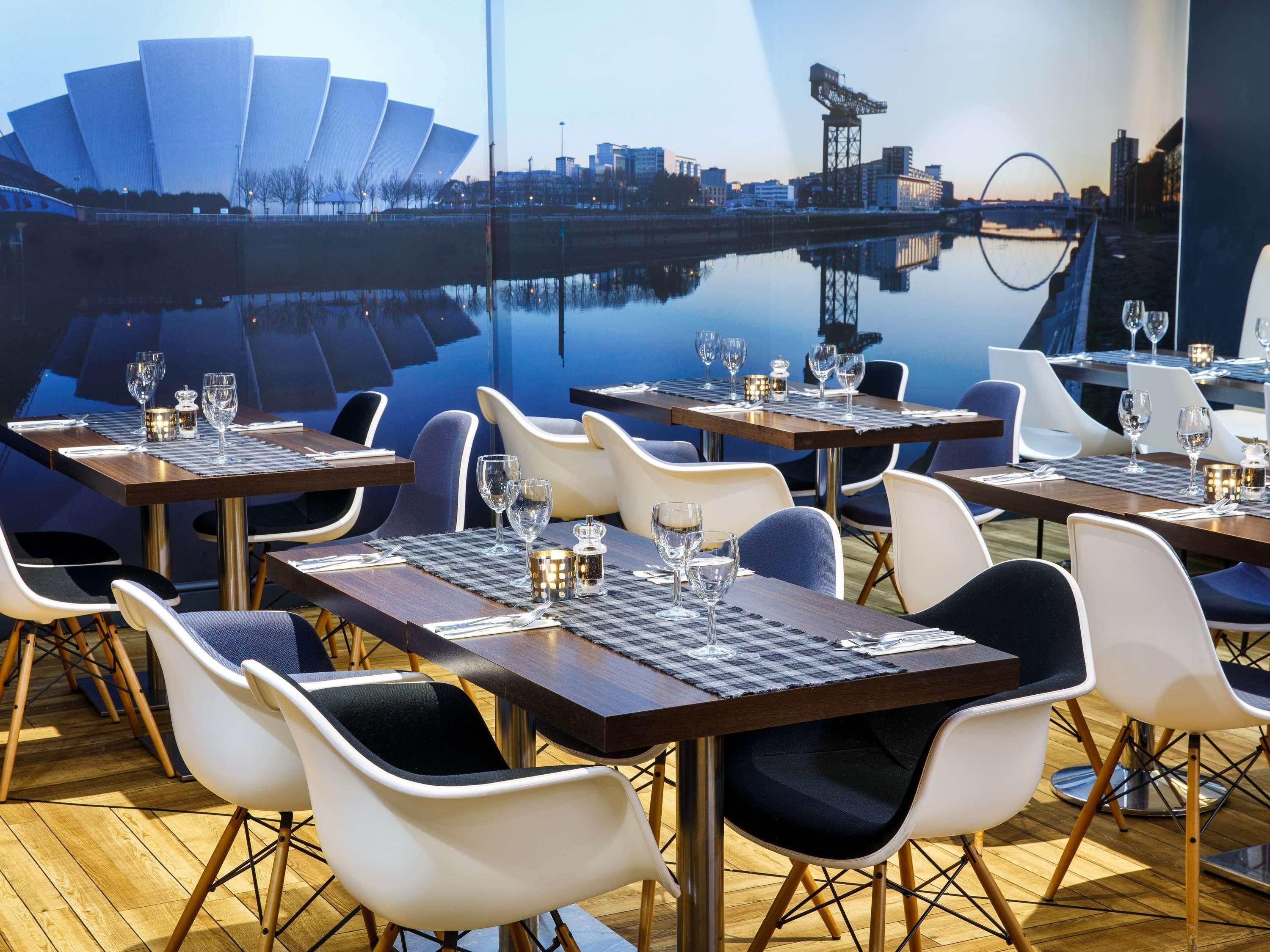 Un restaurante con mesas dispuestas para comer, sillas y vista panorámica de la ciudad.