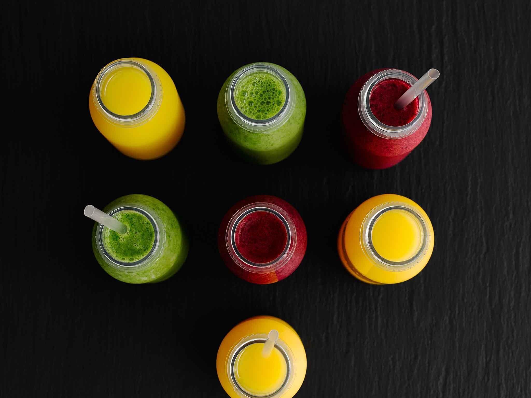 Seis botellas de vidrio con pajitas sobre una superficie oscura.