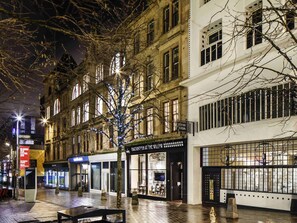 A nighttime urban street with buildings, a tree with lights, and storefronts. - Ibis Glasgow City Centre – Sauchiehall St (Glasgow)