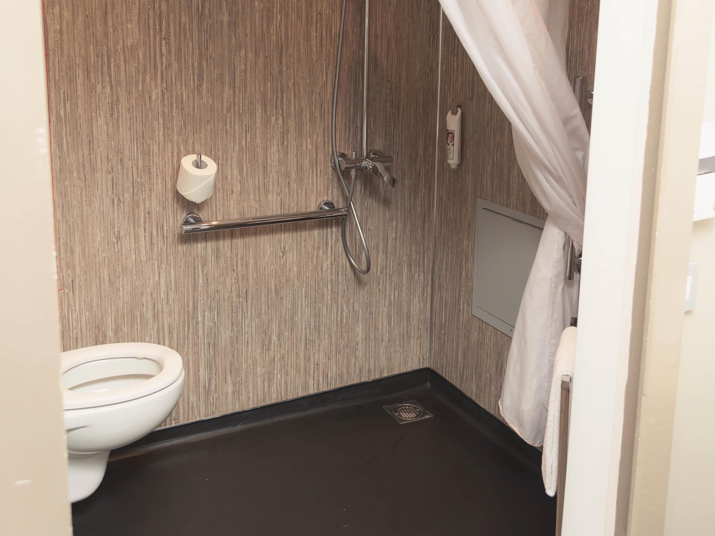 A small bathroom with a toilet, a shower, and a towel rack.