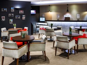 Eine Hotelhalle mit mehreren runden Tischen, Stühlen und einer Rezeption.