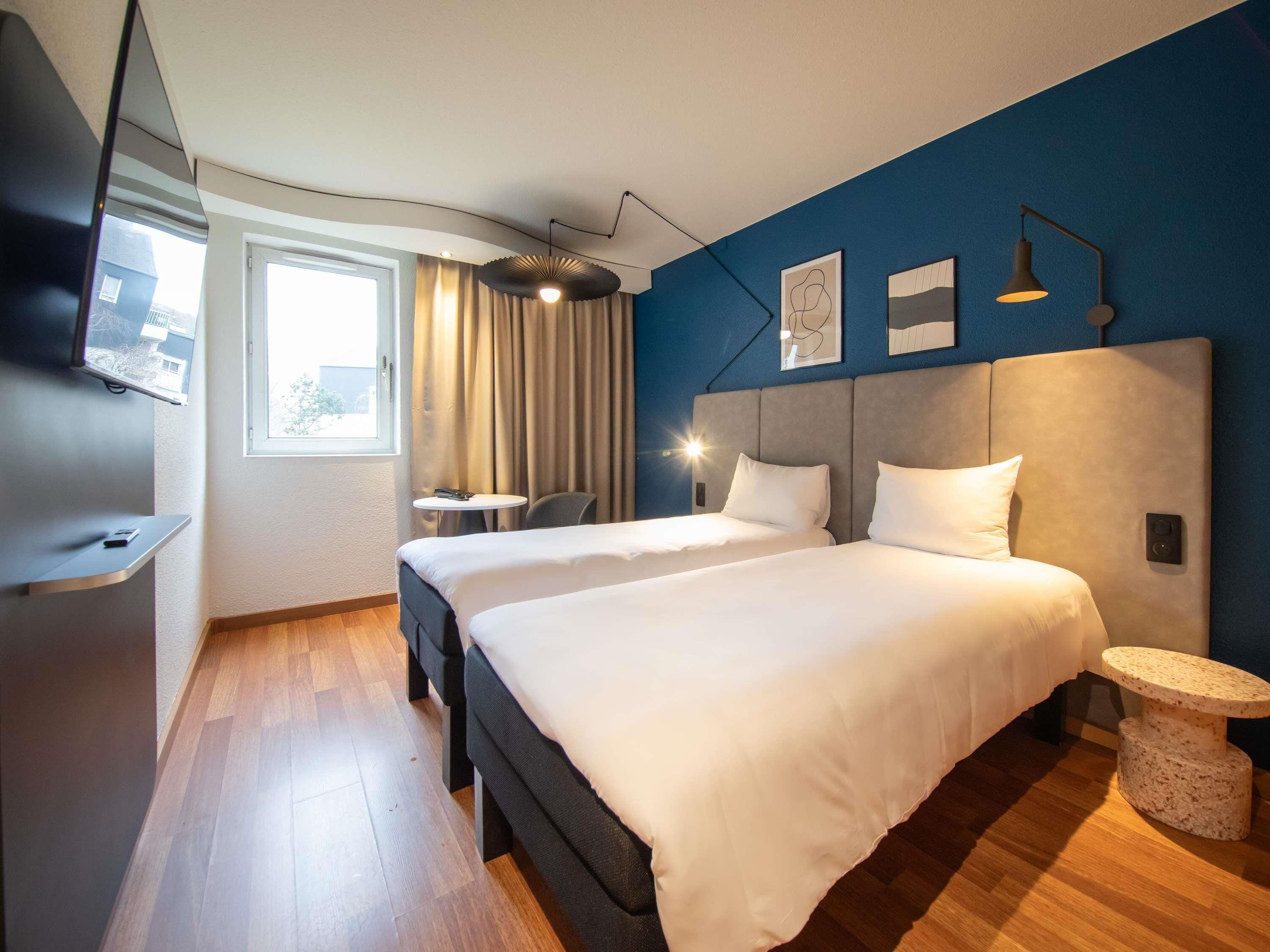 A modern hotel room with a large bed, a desk, and a TV.