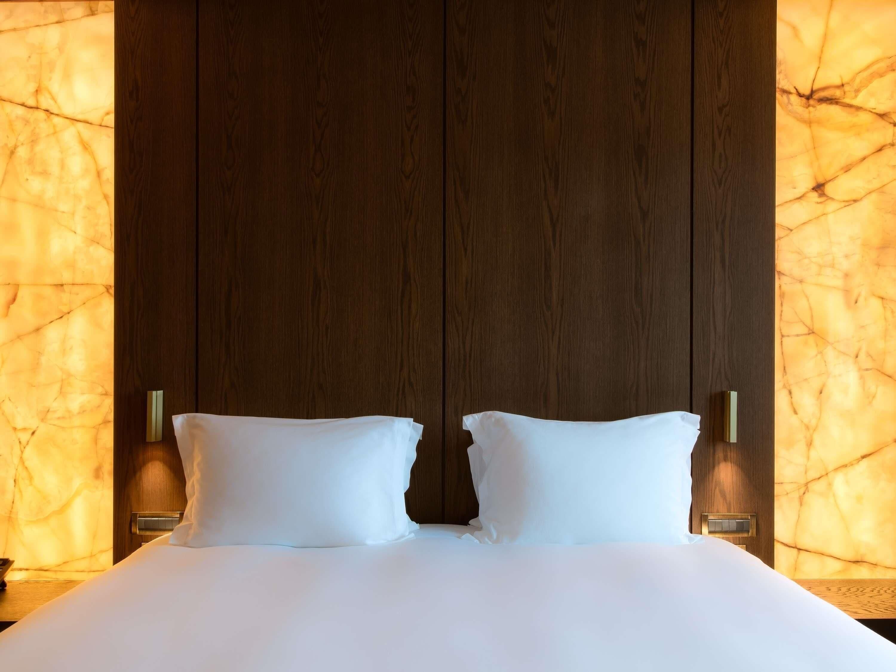 Una habitación de hotel con una cama grande, dos mesitas de noche y una pared de mármol.