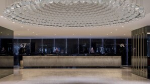Un hall d’entrée doté d’un comptoir de réception moderne, d’un grand lustre et de murs en marbre.