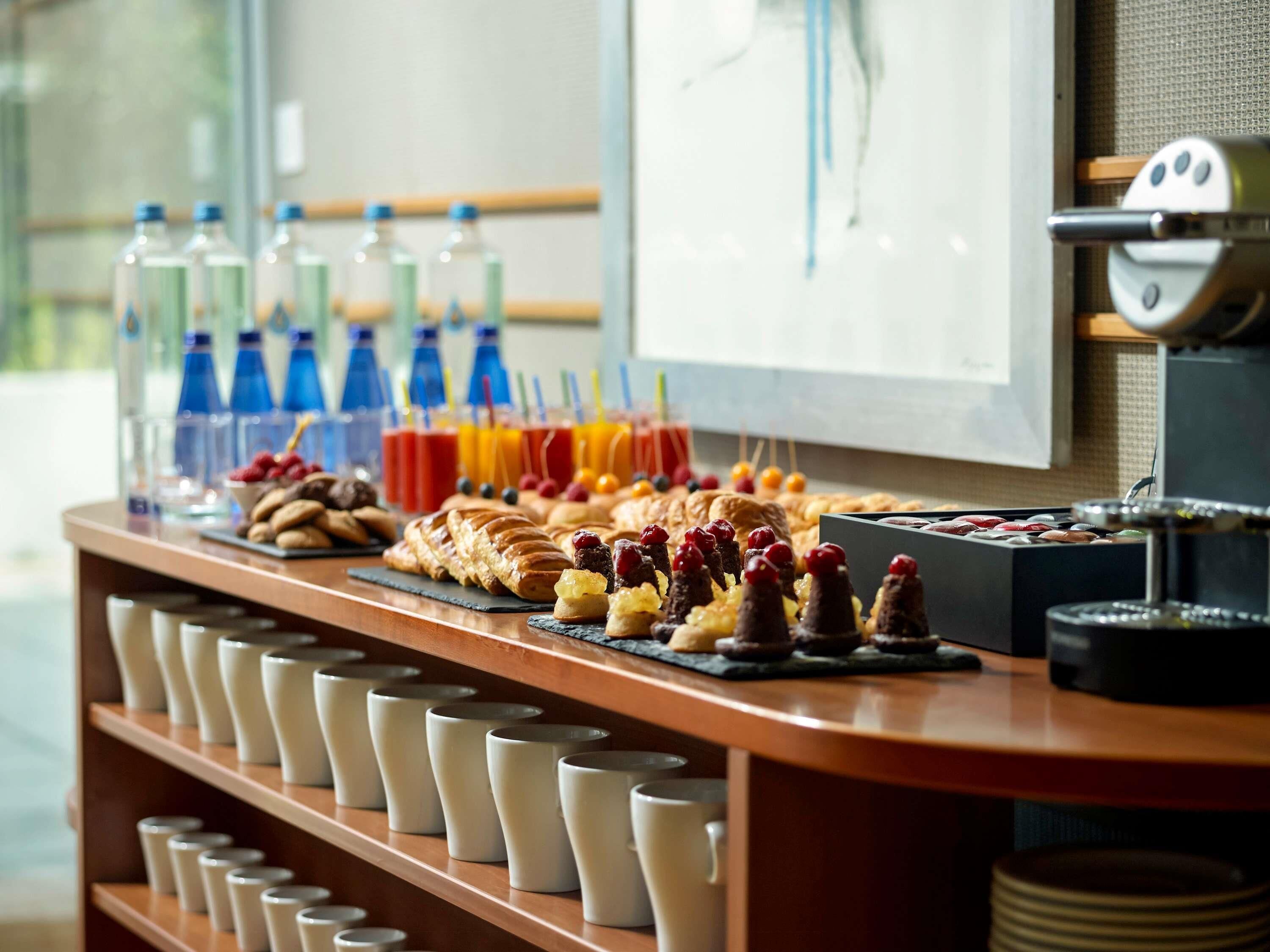 A buffet with various food items, beverages, and cups.