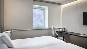 Une chambre d’hôtel moderne équipée d’un lit, d’un bureau, d’une chaise, d’une fenêtre et d’un téléviseur à écran plat.