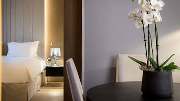 Una habitación de hotel con una cama, mesita de noche, lámpara y una orquídea en maceta.
