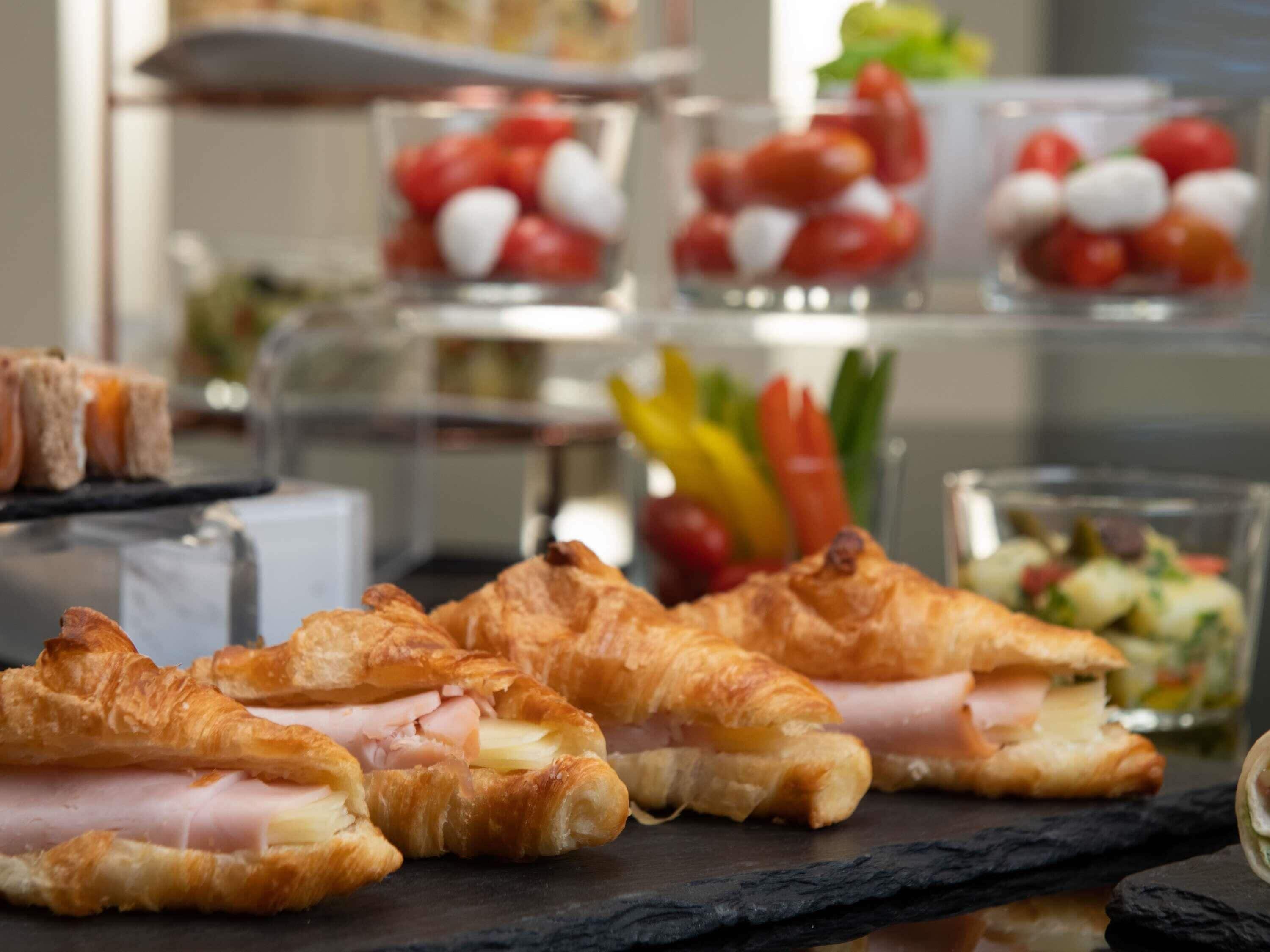 Un bufé con croissants, tomates y una ensalada.