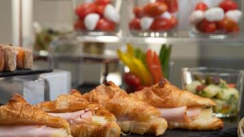 Un bufé con croissants, tomates y una ensalada.