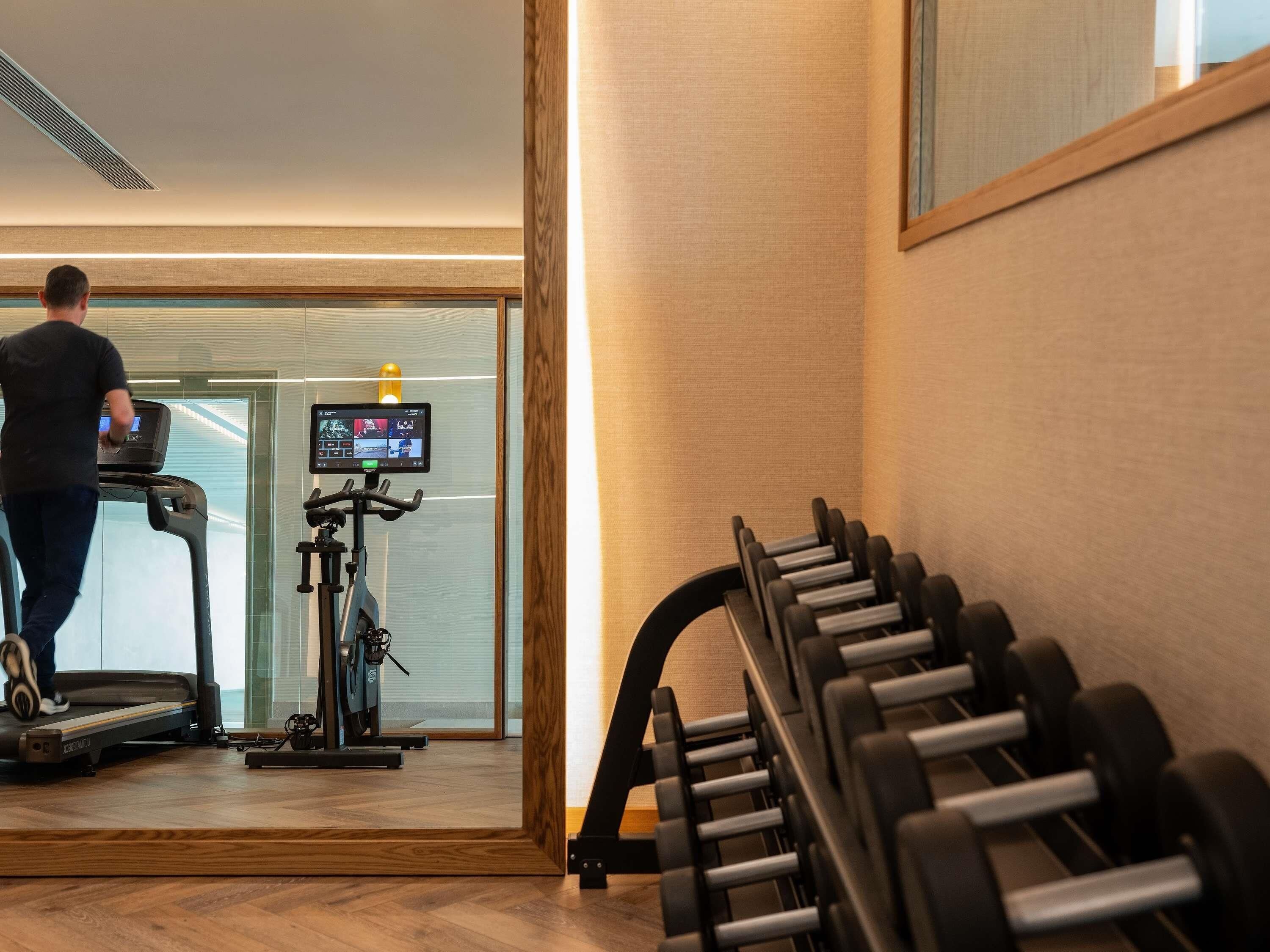 A gym with a treadmill, stationary bike, and a set of dumbbells.