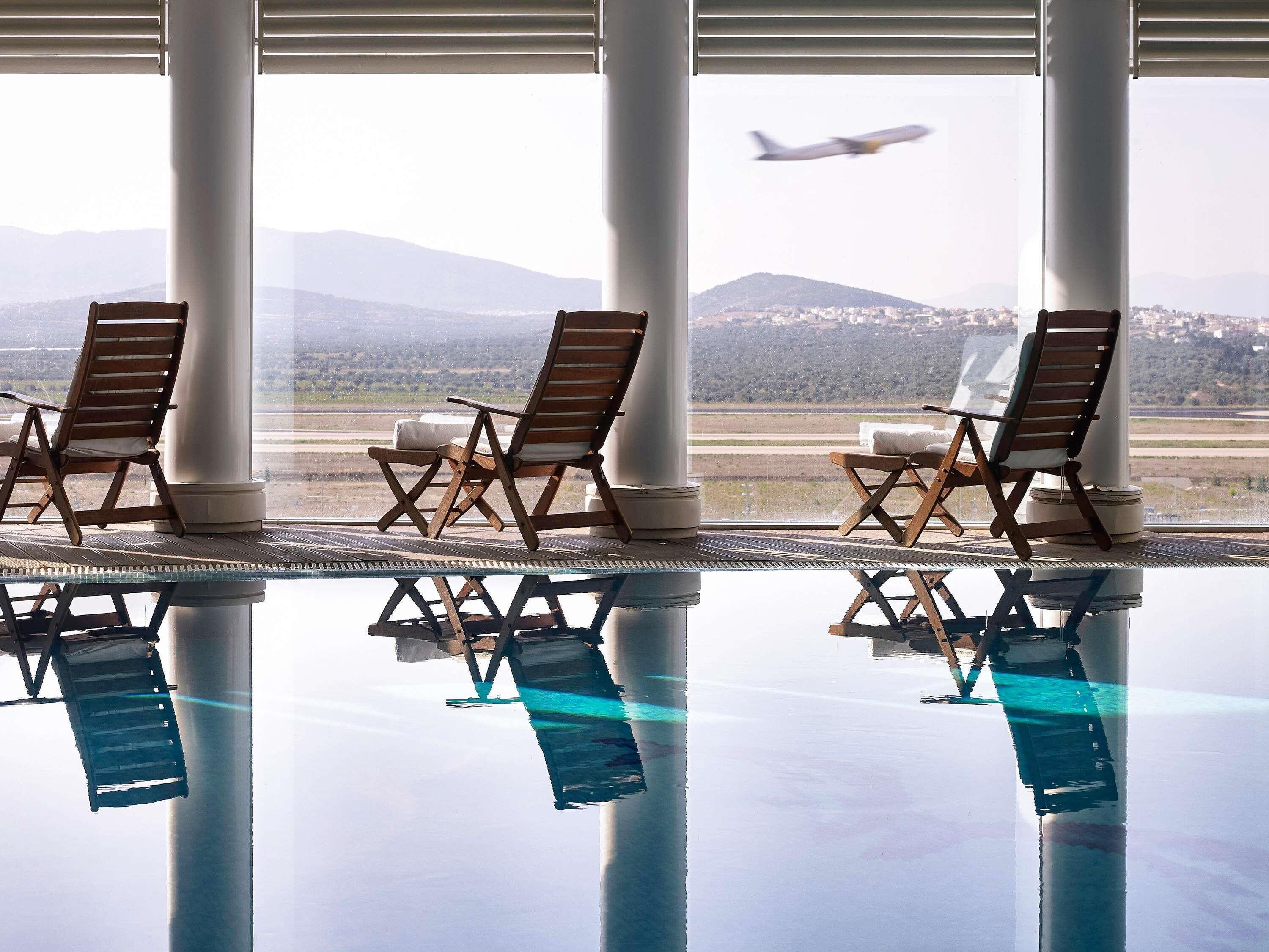 A poolside area with lounge chairs and a view of a mountain and an airplane.