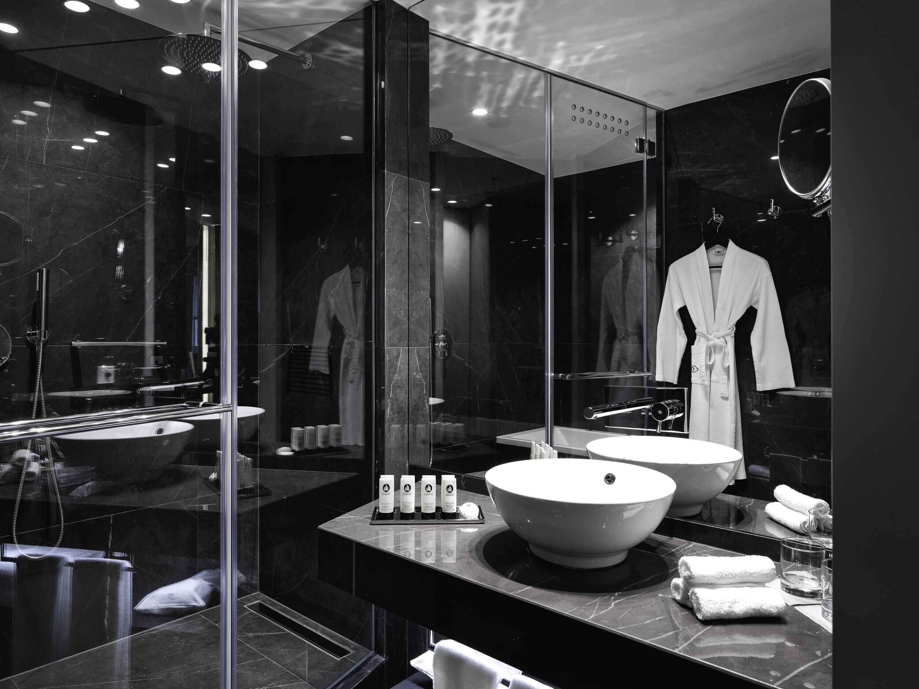 Ein modernes Badezimmer mit einem großen Spiegel, zwei Waschbecken, einer Badewanne und einem Bademantel, der an der Wand hängt.