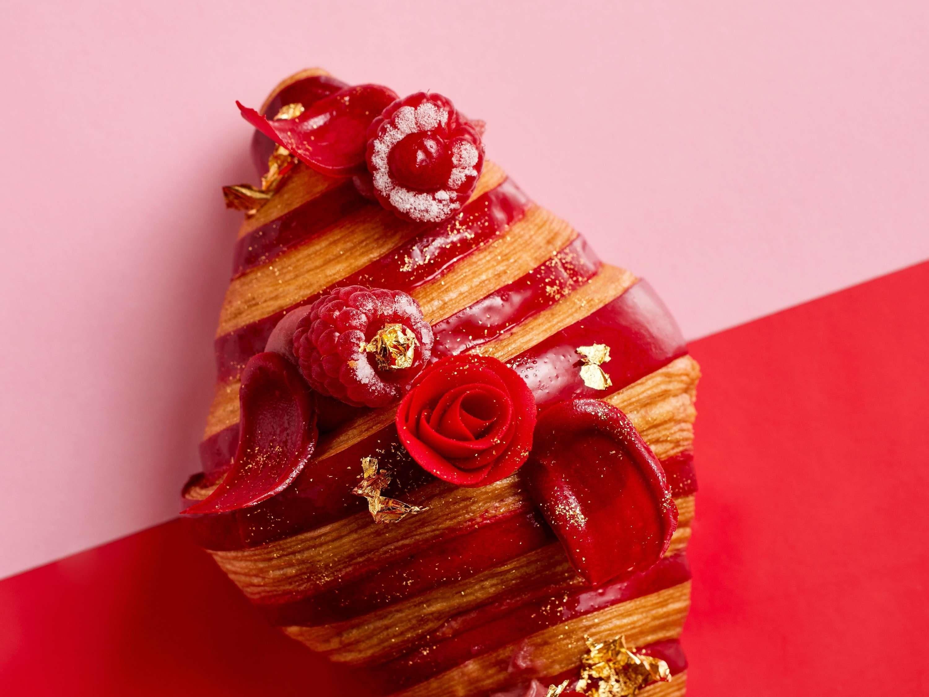 Un postre con superficie roja brillante, detalles decorativos y una hoja dorada.