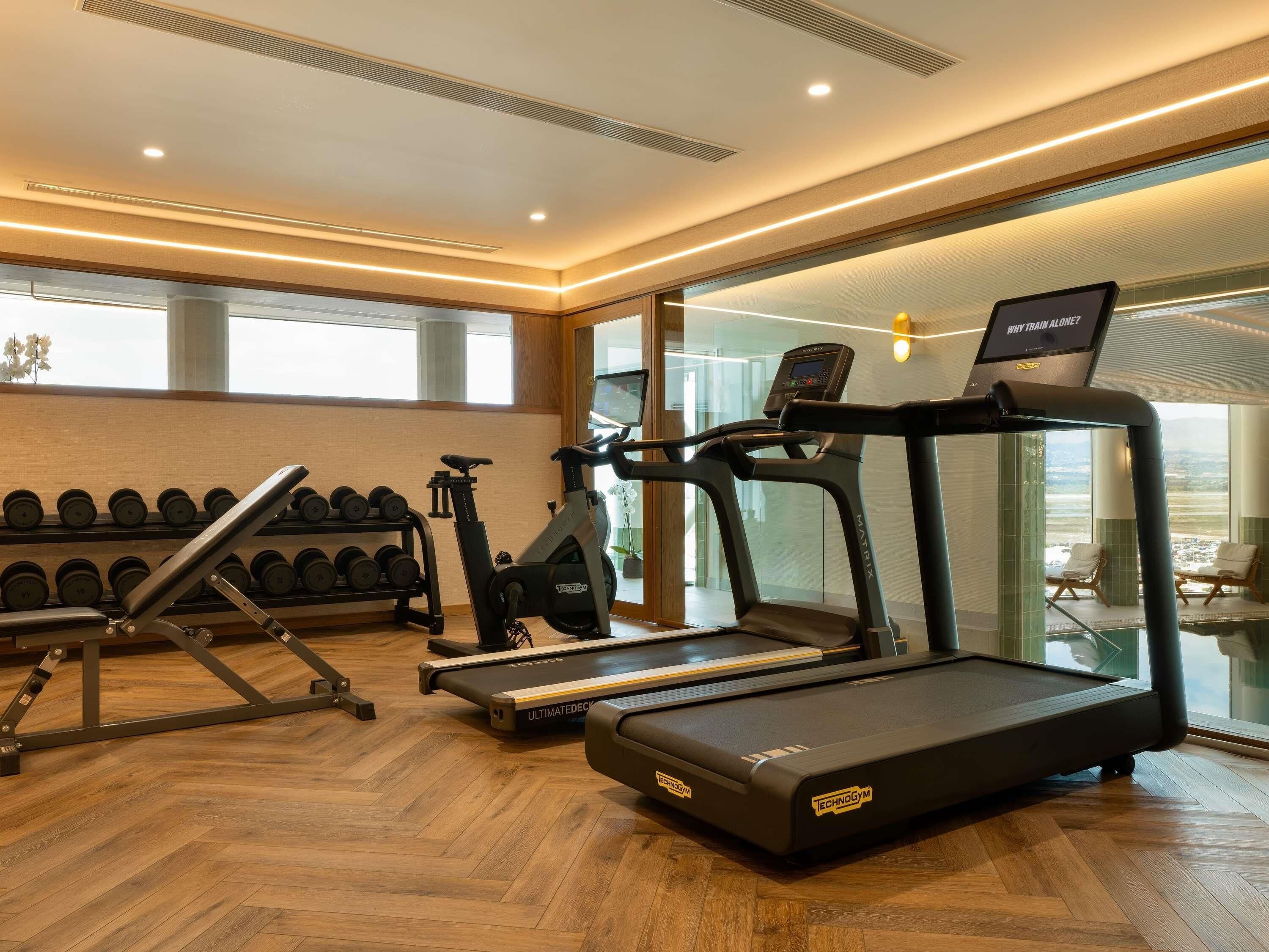 A gym with treadmills, dumbbells, and a rowing machine.