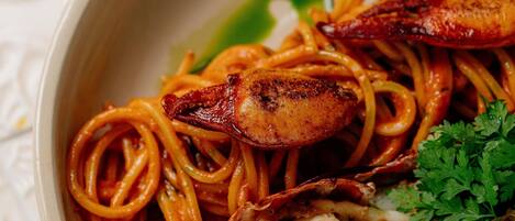 A plate of spaghetti with a lobster tail and a garnish of parsley.