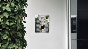 Un pasillo con una obra de arte colgada en la pared que dice '42', una planta en maceta y una puerta de cristal.