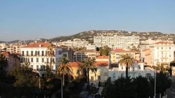 Un paysage urbain côtier mêlant des immeubles résidentiels et commerciaux, dont un bâtiment blanc imposant surmonté d’un toit rouge, et plusieurs palmiers au premier plan.