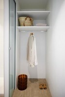 Een kleine, opgeruimde kast met een ophanggedeelte, een mand en een paar slippers.