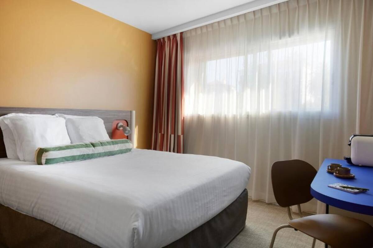 Una habitación de hotel con cama, escritorio y silla.