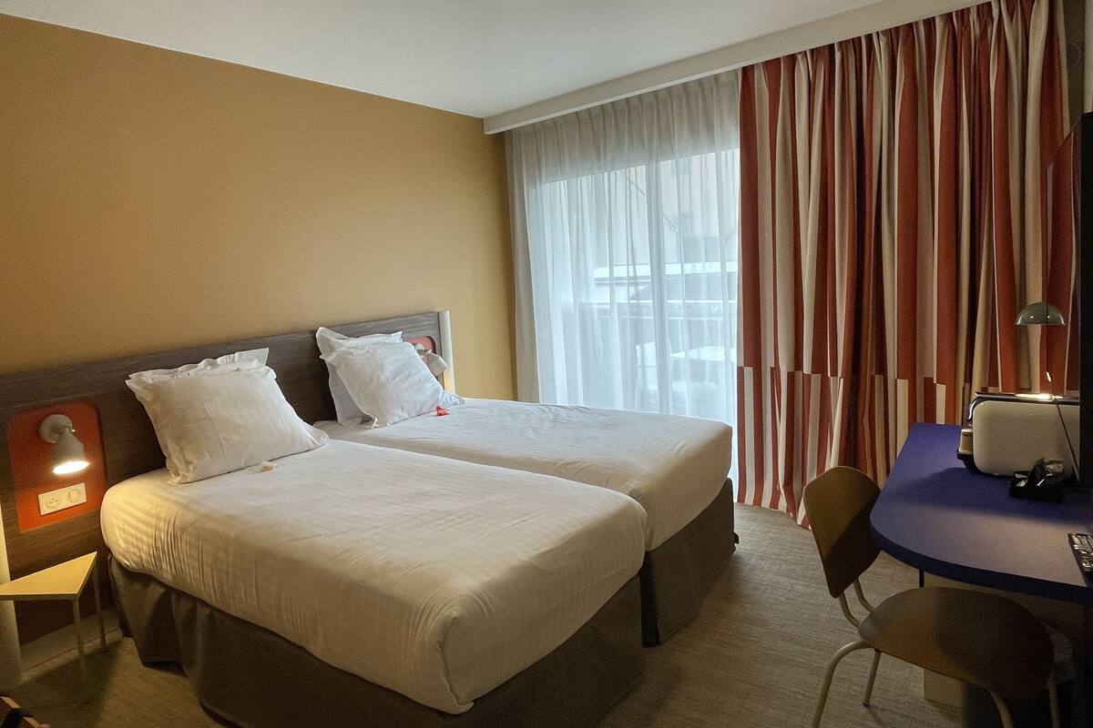 Una habitación de hotel con dos camas, un escritorio y una silla.