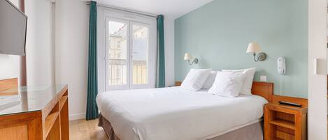 Quarto de hotel com cama, mesas de cabeceira de madeira, escrivaninha e televisão.