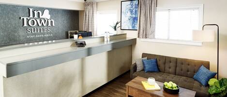 Un espace d’accueil d’hôtel au design moderne, comprenant un comptoir d’accueil, un canapé, une table basse et un ventilateur de plafond.