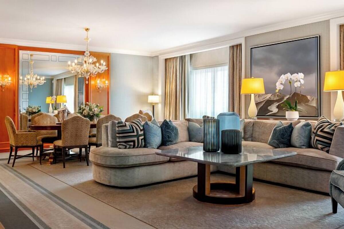 Ein modernes Wohnzimmer mit einem Ecksofa, einem Glastisch und einem Essbereich mit Tisch und Stühlen.