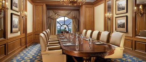 A conference room with a large oval table, leather chairs, and a chandelier.