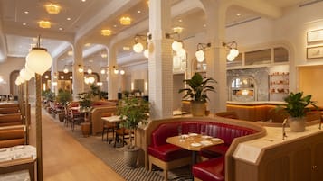 A spacious restaurant with high ceilings, arched columns, and a variety of seating options including booths and tables.