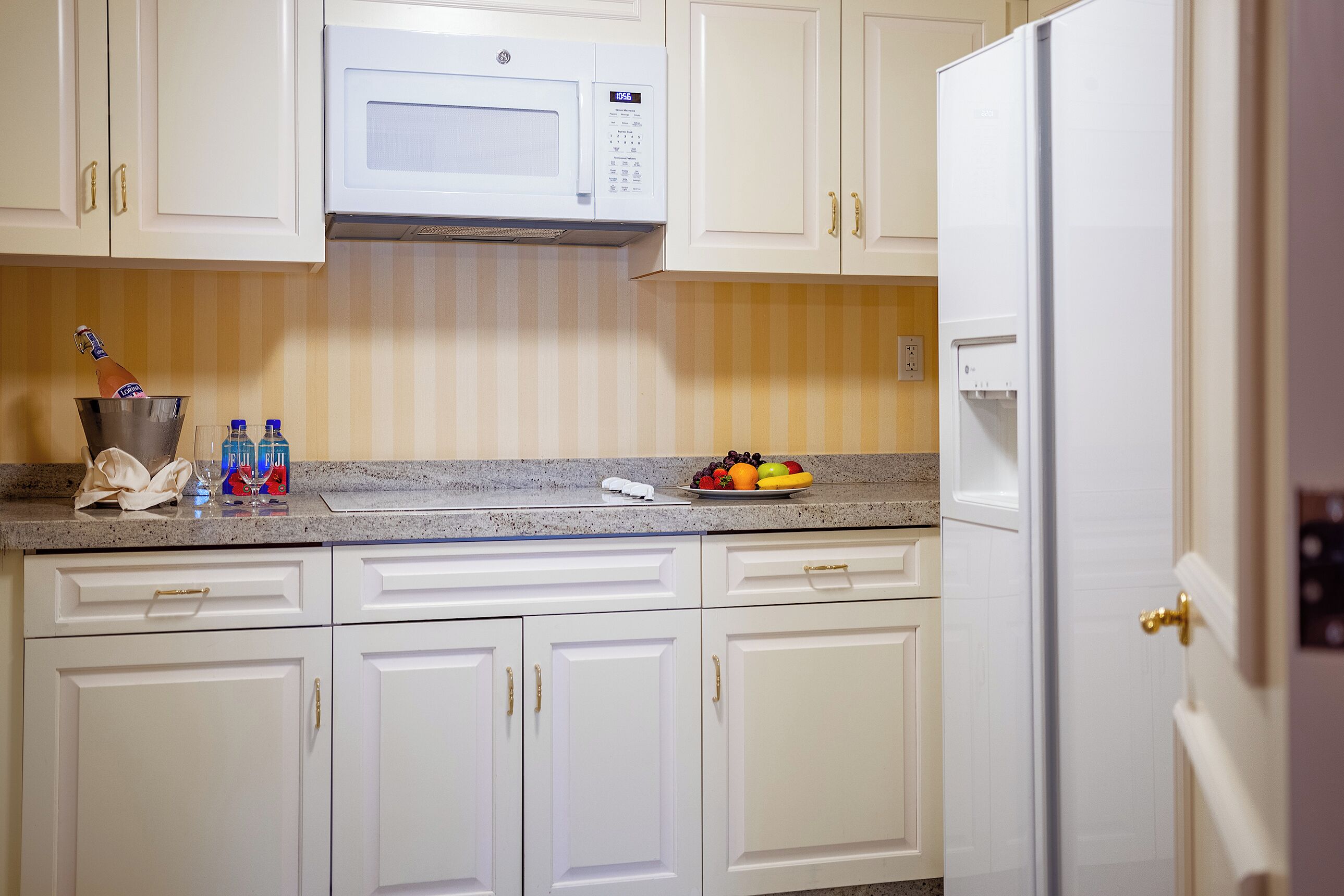 A kitchen with white cabinets, a microwave, and a refrigerator.