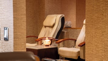 A massage chair with a footrest and a small table with a lamp.