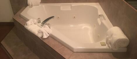 A rectangular bathtub with a built-in seat, a handheld showerhead, and a control panel.