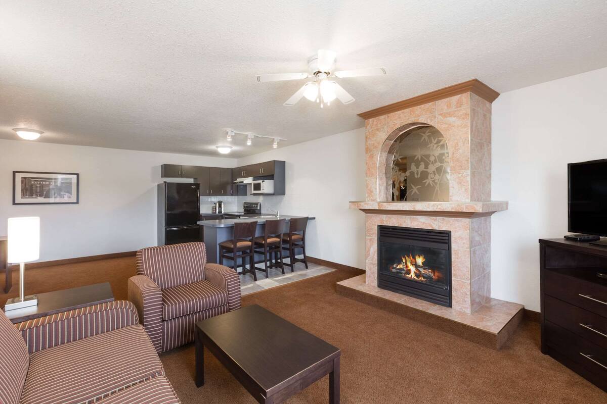 A living room with a fireplace, a dining area, and a kitchen in the background.
