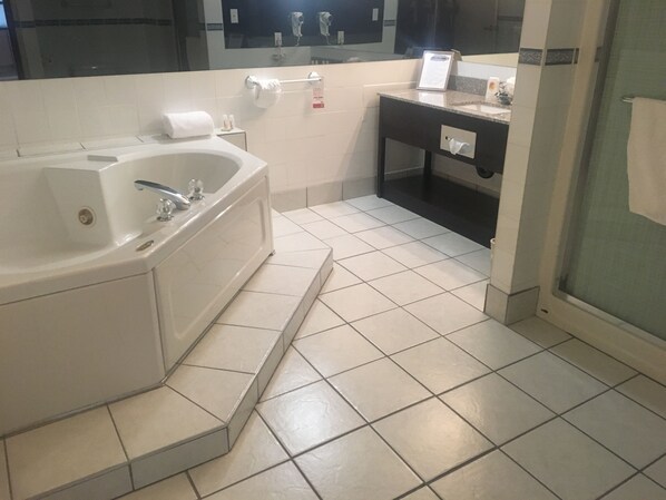 Un baño moderno con una bañera grande, un tocador con espejo y una zona de ducha.