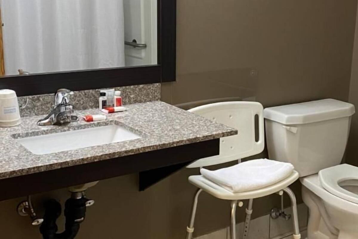 A bathroom with a sink, toilet, and a mirror.