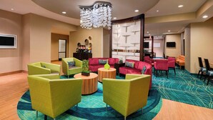 Eine Hotellobby mit einer zentralen Sitzecke, einem großen Chandelier und einem gemusterten Teppich.
