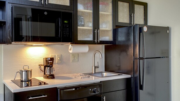 Una cocina con un refrigerador de acero inoxidable, un microondas y una cafetera.