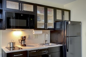 Una cocina con un refrigerador de acero inoxidable, un microondas y una cafetera.